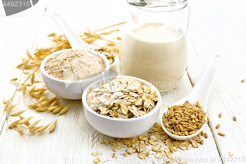 Image of Oat flakes with flour and milk on white wooden board