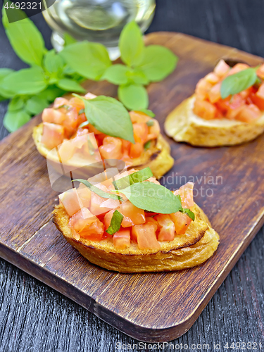 Image of Bruschetta with tomato and basil on black board