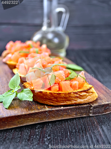 Image of Bruschetta with tomato and basil on black wooden board