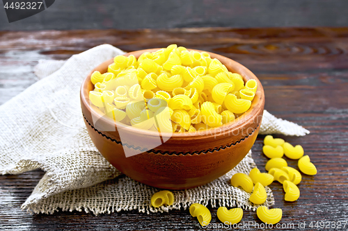 Image of Elbow macaroni in bowl with burlap on board