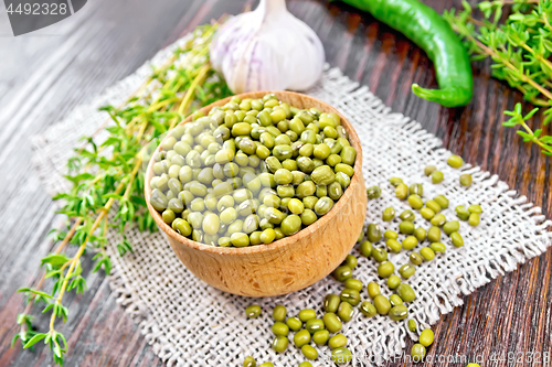 Image of Mung beans in wooden bowl with thyme and pepper on dark board