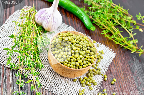 Image of Mung beans in wooden bowl with thyme and pepper on board