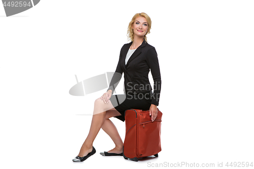 Image of business woman sitting on travel case