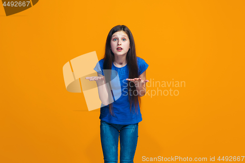 Image of Beautiful female half-length portrait on orange studio backgroud. The young emotional teen girl