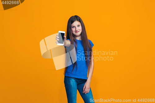 Image of The happy teen girl standing and smiling against orange background.