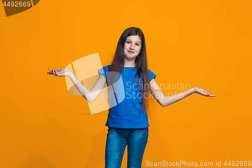 Image of Beautiful teen girl looking suprised and bewildered isolated on orange