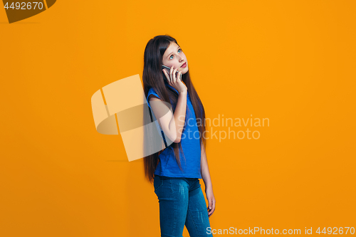 Image of The happy teen girl standing and smiling against orange background.