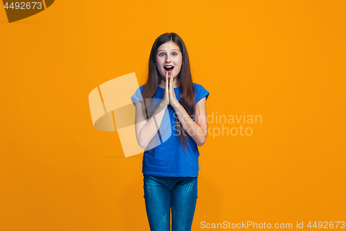 Image of Beautiful teen girl looking suprised isolated on orange