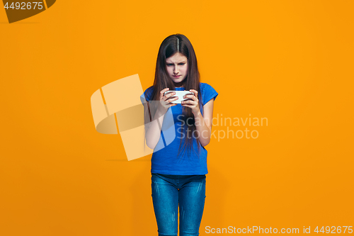 Image of The happy teen girl standing and smiling against orange background.