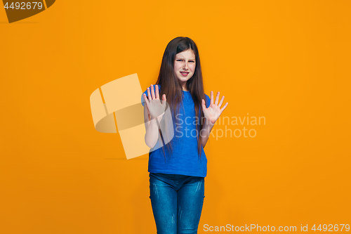 Image of Doubtful pensive teen girl rejecting something against orange background