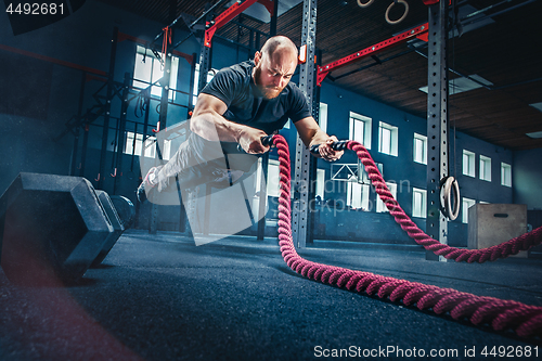 Image of Men with battle rope battle ropes exercise in the fitness gym.