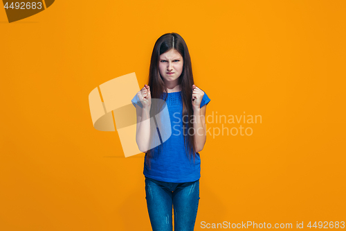 Image of Portrait of angry teen girl on a orange studio background