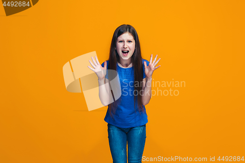 Image of Portrait of angry teen girl on a orange studio background