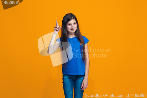 Image of The happy teen girl standing and smiling against orange background.