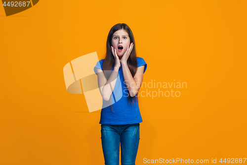 Image of Beautiful teen girl looking suprised isolated on orange