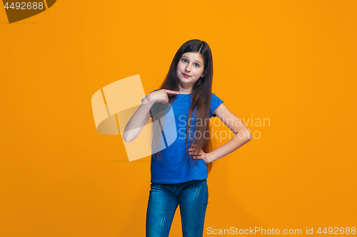 Image of The happy teen girl standing and smiling against orange background.