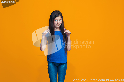 Image of The happy teen girl standing and smiling against orange background.