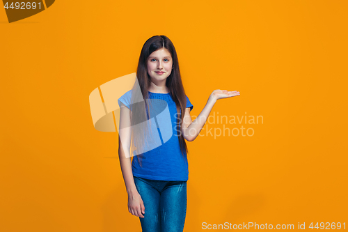 Image of The happy teen girl standing and smiling against orange background.