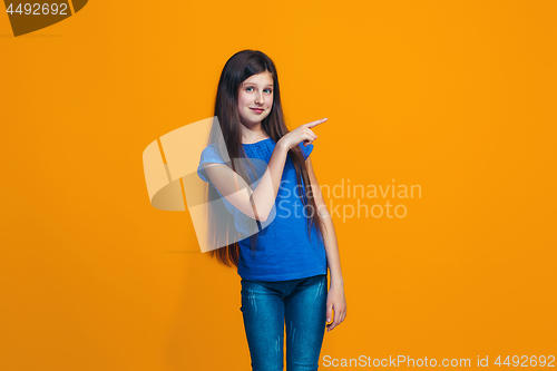 Image of The happy teen girl standing and smiling against orange background.