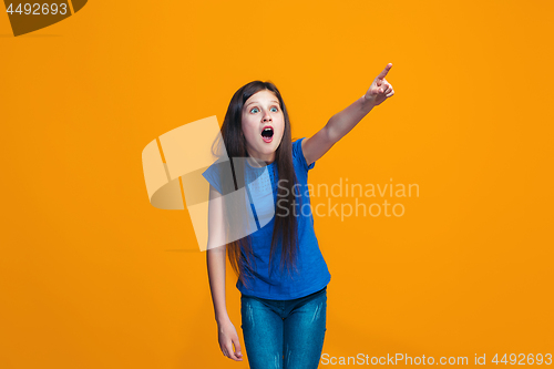 Image of Beautiful teen girl looking suprised isolated on orange