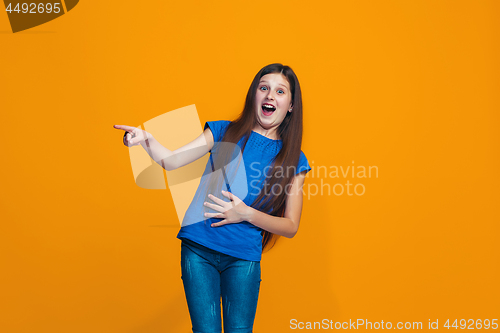 Image of The happy teen girl standing and smiling against orange background.