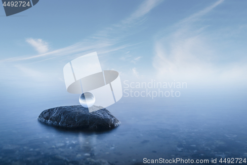 Image of Crystal ball on a rock in a misty seascape