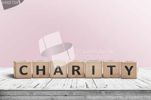 Image of Charity sign on a wooden desk with a pink wall