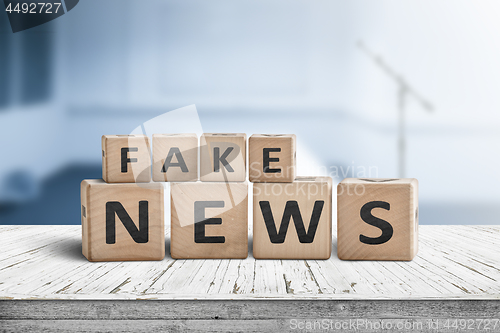 Image of Fake news sign on a wooden desk in a blue room