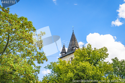 Image of Fairytale castle tower rising up behind green trees