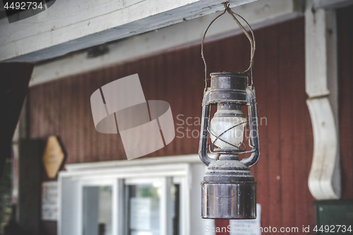 Image of Old oil lamp hanging on a porch outside