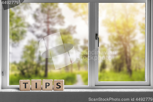 Image of Tips sign in a window with a view to a green garden