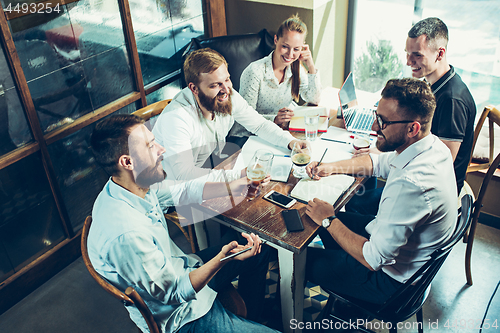 Image of Young cheerful people smile and gesture while relaxing in pub.