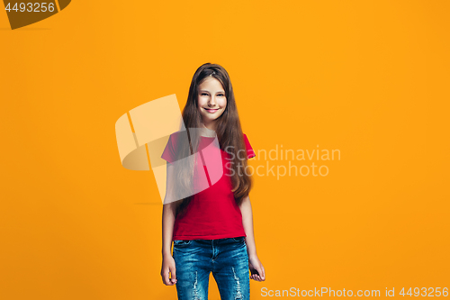 Image of The happy teen girl pointing to you, half length closeup portrait on orange background.