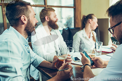 Image of Young cheerful people smile and gesture while relaxing in pub.