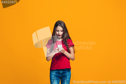 Image of The happy teen girl standing and smiling against orange background.