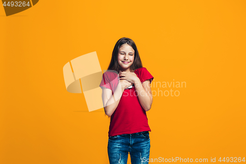 Image of The happy teen girl standing and smiling against orange background.