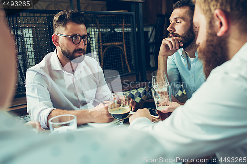 Image of Young cheerful people smile and gesture while relaxing in pub.