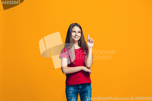 Image of The happy teen girl standing and smiling against orange background.