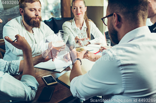 Image of Young cheerful people smile and gesture while relaxing in pub.