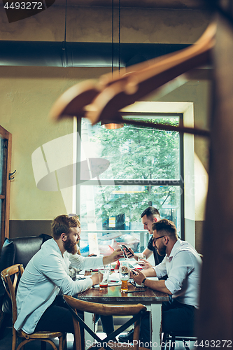 Image of Young cheerful people smile and gesture while relaxing in pub.