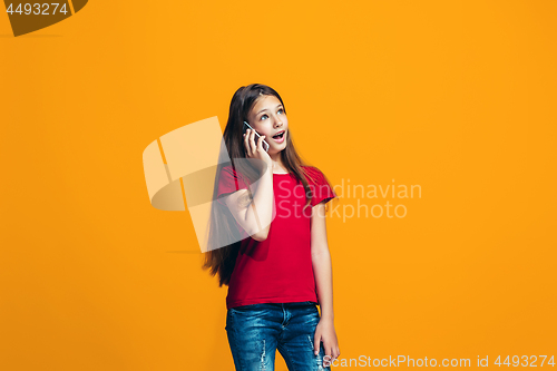 Image of The happy teen girl standing and smiling against orange background.