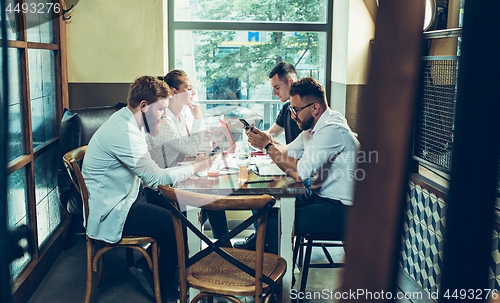 Image of Young cheerful people smile and gesture while relaxing in pub.