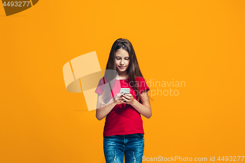 Image of The happy teen girl standing and smiling against orange background.