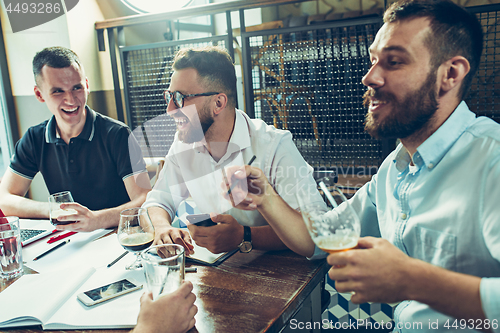 Image of Young cheerful people smile and gesture while relaxing in pub.