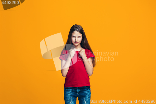 Image of Portrait of angry teen girl on a orange studio background