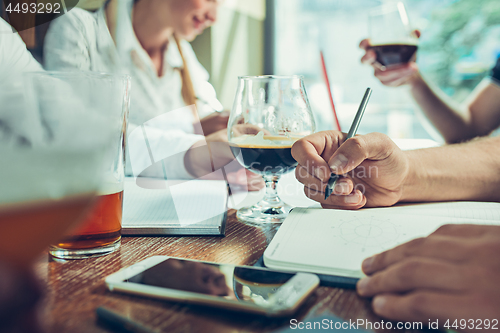 Image of Young cheerful people smile and gesture while relaxing in pub.