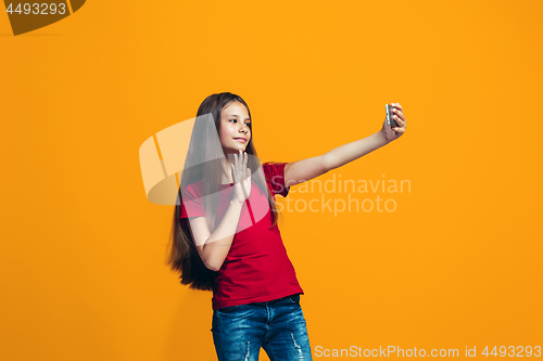 Image of The happy teen girl standing and smiling against orange background.
