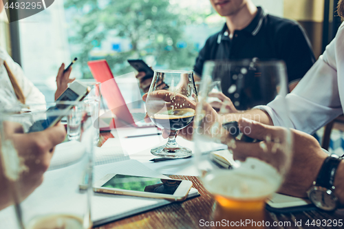 Image of Young cheerful people smile and gesture while relaxing in pub.