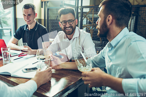 Image of Young cheerful people smile and gesture while relaxing in pub.