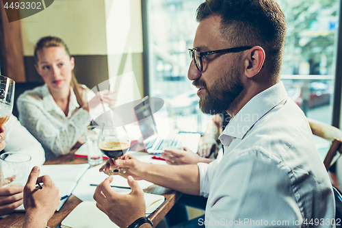 Image of Young cheerful people smile and gesture while relaxing in pub.